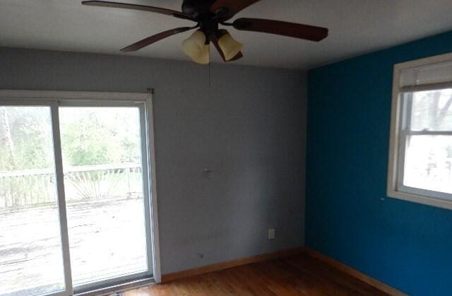 empty room with baseboards, a ceiling fan, and wood finished floors