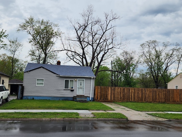 view of side of property featuring a lawn, fence, and a chimney