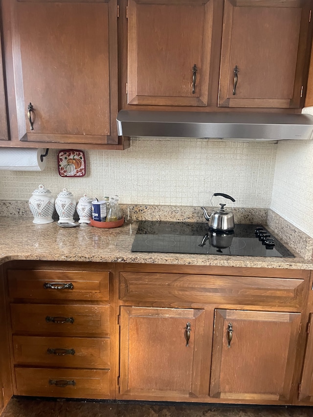 11916 Geoffry Dr, Warren, MI 48093 - kitchen featuring brown cabinets, light stone counters, black electric stovetop, wall chimney exhaust hood, and tasteful backsplash