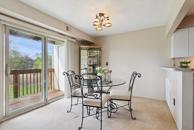 dining area with visible vents, a chandelier, and light carpet