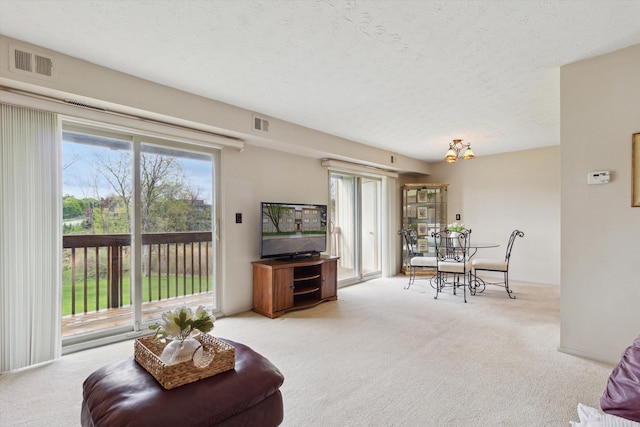 carpeted living room featuring a textured ceiling and visible vents