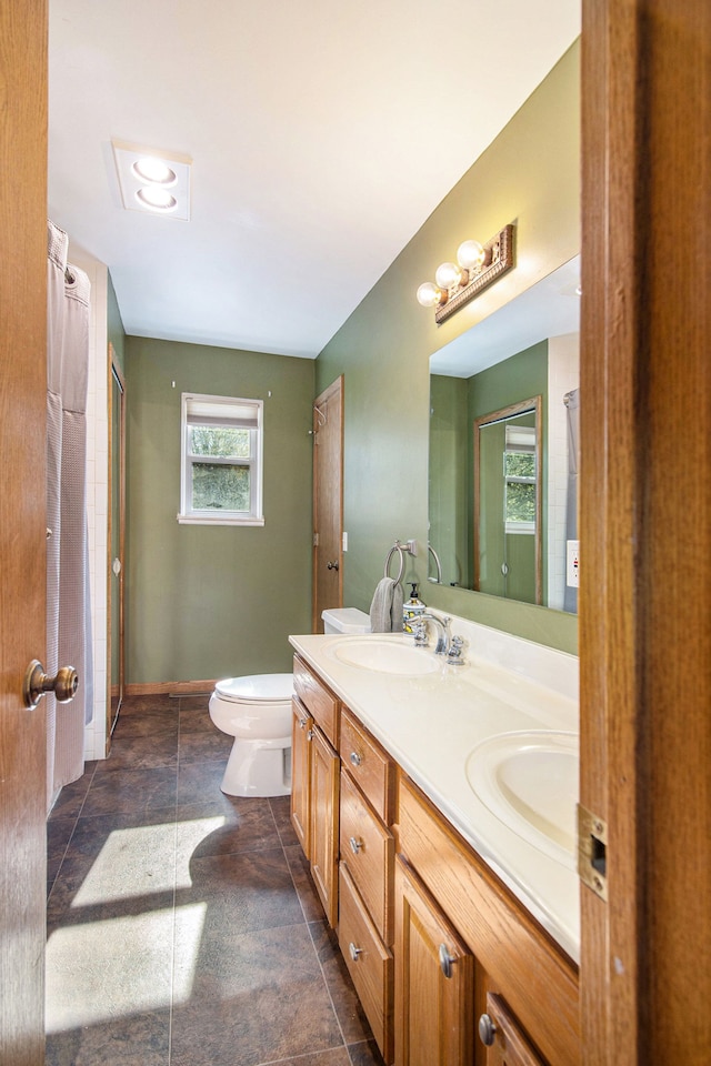 bathroom featuring double vanity, toilet, and baseboards