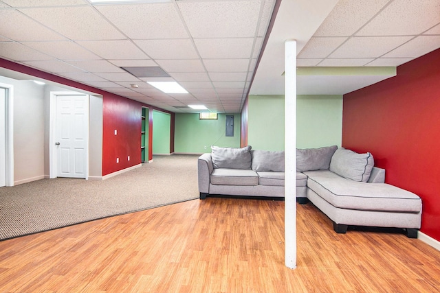 living room featuring baseboards, wood finished floors, a paneled ceiling, and electric panel