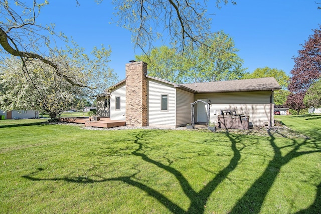 back of house featuring a deck, a lawn, and a chimney