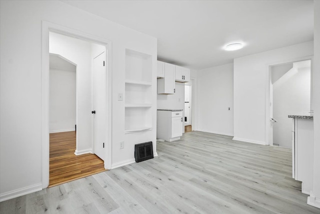 unfurnished living room featuring baseboards, visible vents, and light wood-style flooring