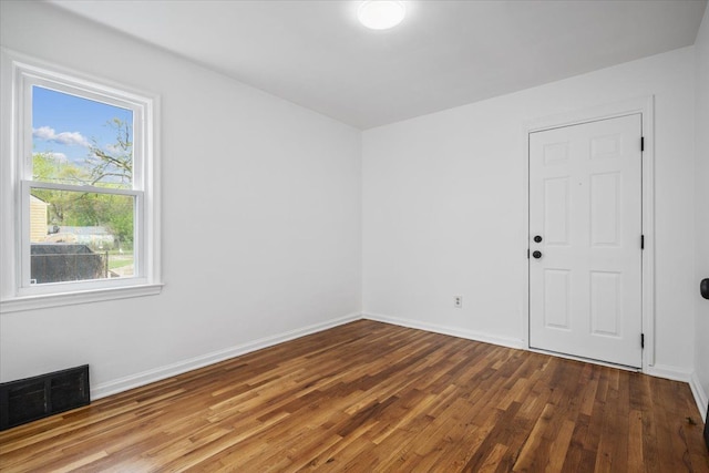 spare room featuring baseboards, visible vents, and wood finished floors