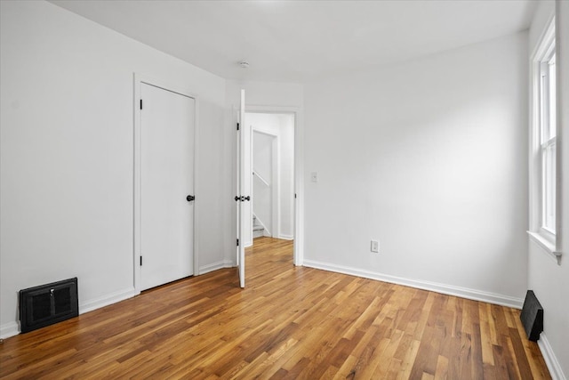empty room with baseboards, visible vents, and light wood finished floors