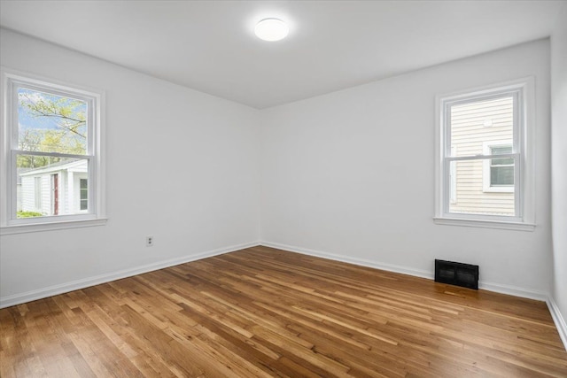 spare room with baseboards, visible vents, and wood finished floors