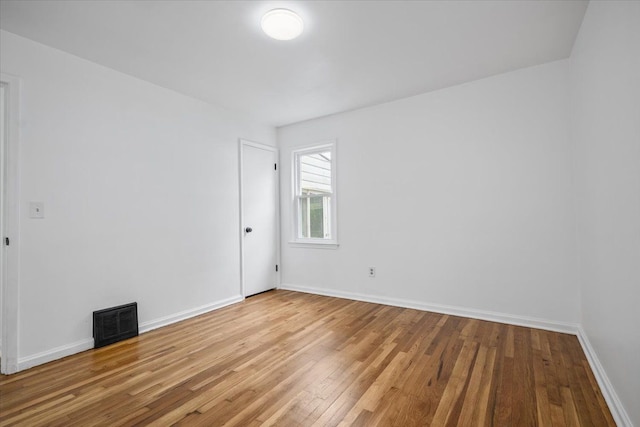 unfurnished room with baseboards, hardwood / wood-style flooring, and visible vents