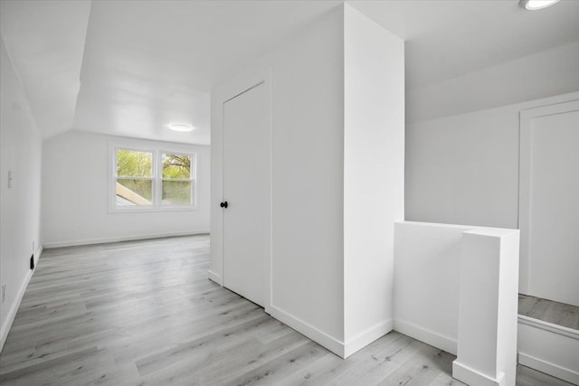 additional living space featuring baseboards, wood finished floors, and lofted ceiling