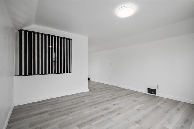 empty room with baseboards, vaulted ceiling, and wood finished floors