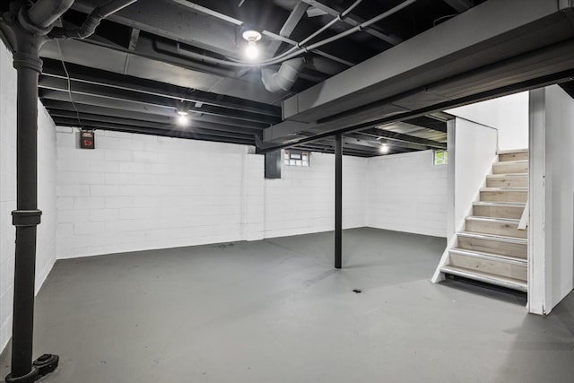 basement with a wealth of natural light, electric panel, and stairway