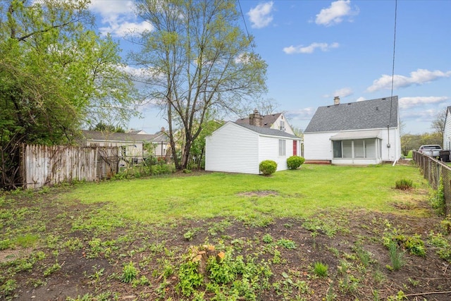 view of yard with a storage unit, a fenced backyard, and an outbuilding
