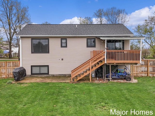 rear view of house with a wooden deck, fence, a shingled roof, a yard, and stairway
