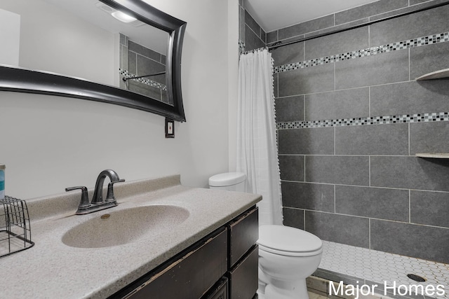 bathroom with vanity, toilet, and tiled shower