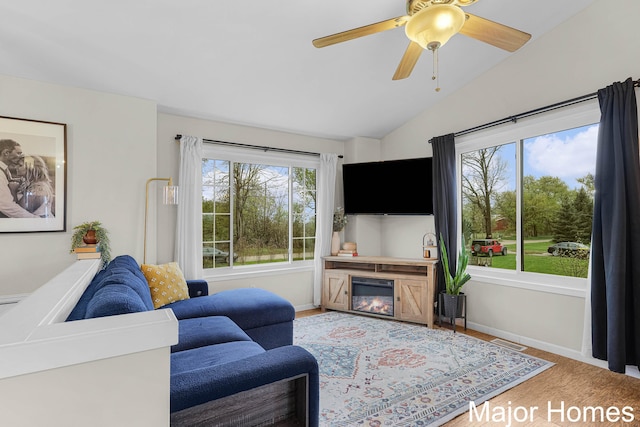 living room with a glass covered fireplace, baseboards, vaulted ceiling, and visible vents