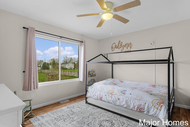 bedroom with baseboards, ceiling fan, wood finished floors, and visible vents