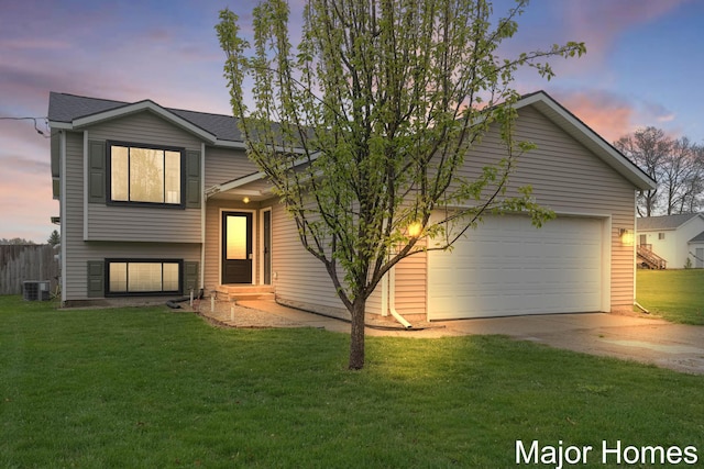 view of front of house with a lawn, an attached garage, driveway, and cooling unit