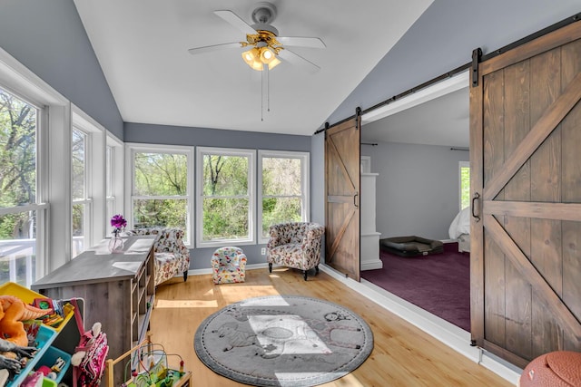 sunroom / solarium with baseboards, vaulted ceiling, a barn door, and wood finished floors