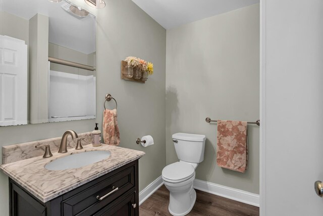 bathroom featuring vanity, baseboards, wood finished floors, and toilet