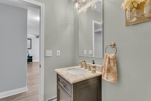 bathroom featuring baseboards, visible vents, wood finished floors, and vanity