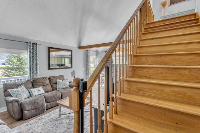 stairway featuring a textured ceiling, vaulted ceiling, and wood finished floors
