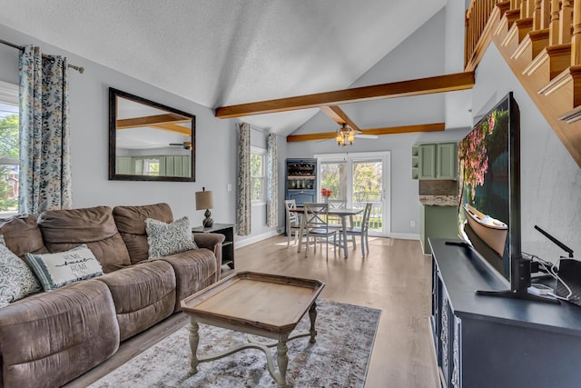 living area featuring lofted ceiling, baseboards, ceiling fan, light wood-type flooring, and a textured ceiling