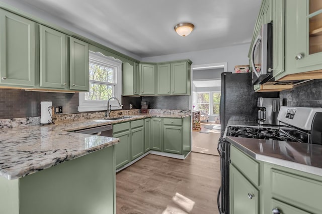 kitchen with a sink, green cabinets, stainless steel appliances, and a healthy amount of sunlight