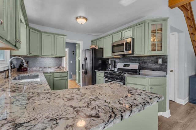 kitchen with green cabinetry, appliances with stainless steel finishes, decorative backsplash, and a sink