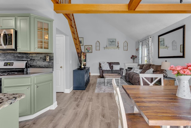 dining space with light wood-type flooring and lofted ceiling with beams