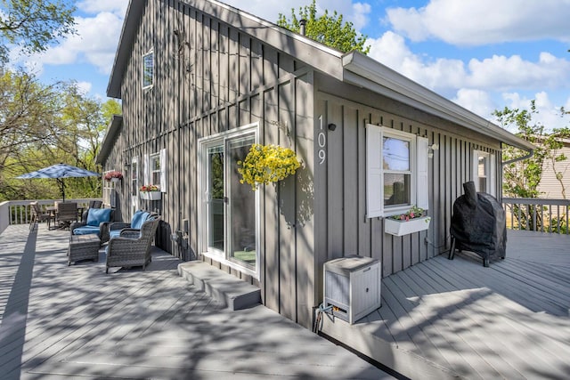 view of side of home with board and batten siding, a deck, and outdoor dining area