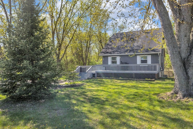 view of front of home featuring roof with shingles, a front yard, and a deck