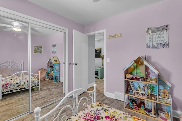 bedroom featuring visible vents, a closet, wood finished floors, baseboards, and a ceiling fan