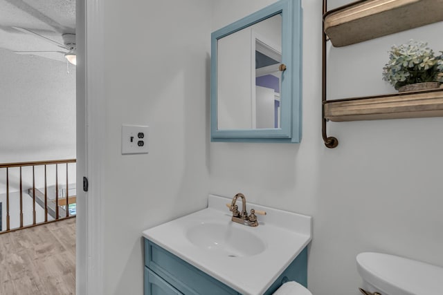 half bath featuring vanity, ceiling fan, toilet, and wood finished floors