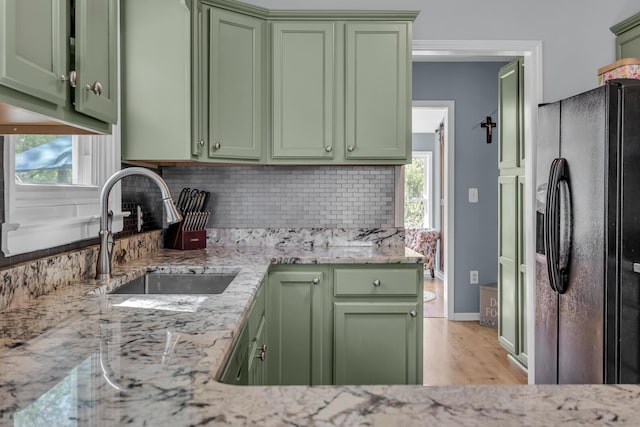 kitchen with a sink, green cabinets, and black fridge with ice dispenser