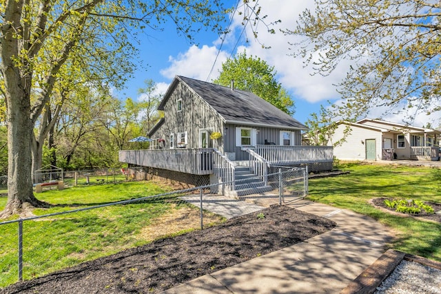 view of front of home featuring fence, a wooden deck, and a front lawn