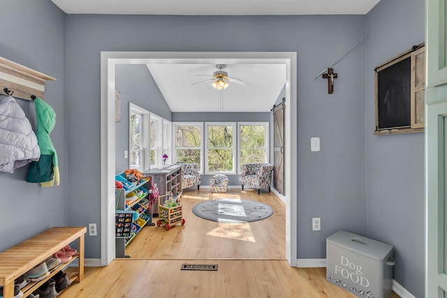 doorway to outside featuring a ceiling fan, baseboards, vaulted ceiling, and wood finished floors