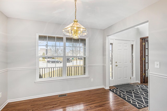 entryway featuring visible vents, baseboards, wood finished floors, and a notable chandelier