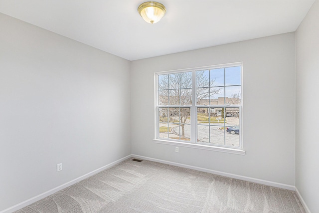 empty room with baseboards, light carpet, and visible vents