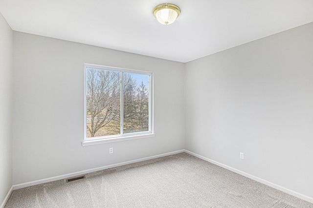 spare room featuring visible vents, carpet, and baseboards