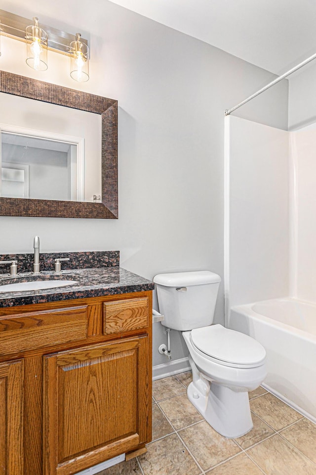bathroom featuring tile patterned flooring, vanity, toilet, baseboards, and shower / washtub combination