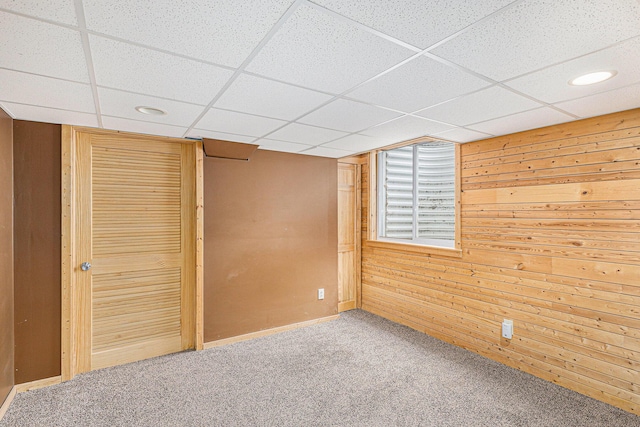 interior space with carpet floors, wood walls, a paneled ceiling, recessed lighting, and baseboards