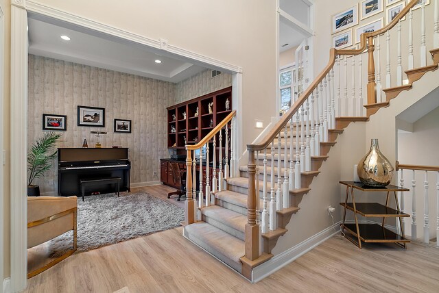 staircase featuring recessed lighting, baseboards, wallpapered walls, and wood finished floors