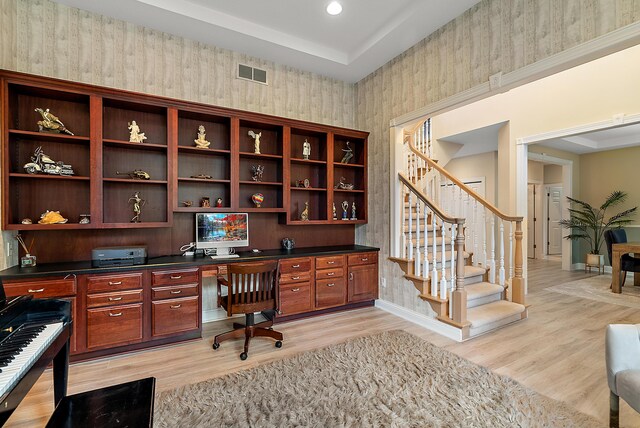 office space with visible vents, built in desk, baseboards, wallpapered walls, and light wood-style flooring