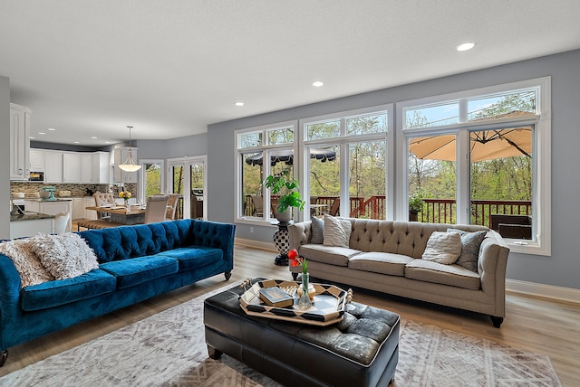 living room with baseboards, light wood-type flooring, and recessed lighting