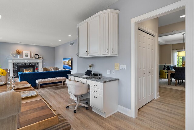 bedroom featuring visible vents, baseboards, recessed lighting, light wood-style flooring, and a premium fireplace