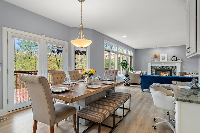 dining space with french doors, visible vents, light wood-type flooring, recessed lighting, and a premium fireplace