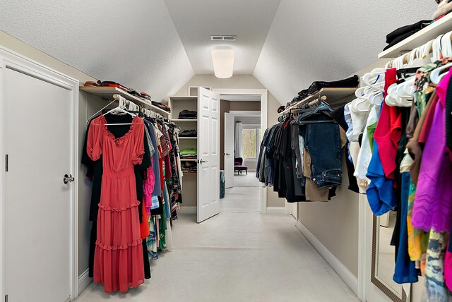 spacious closet with carpet floors, vaulted ceiling, and visible vents