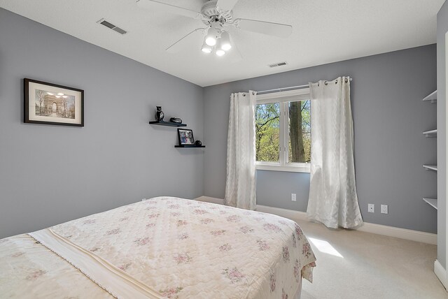 carpeted bedroom with visible vents, a ceiling fan, and baseboards
