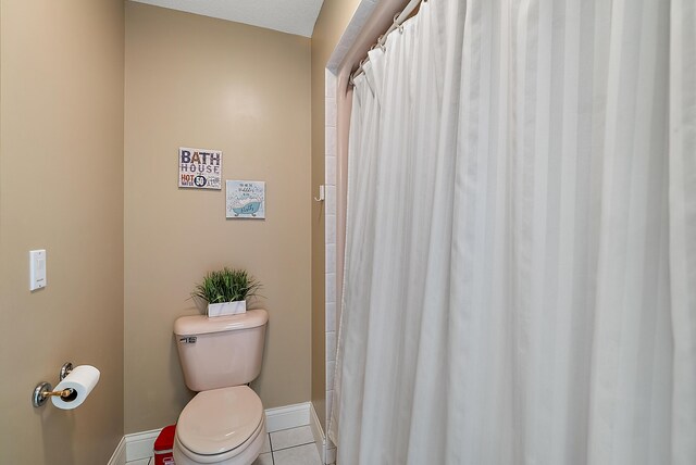 full bath featuring toilet, baseboards, a shower with curtain, and tile patterned flooring